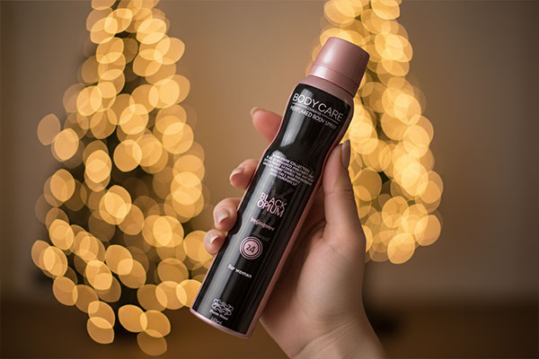 اسپری بدن زنانه بلک اپیوم بادی کر در دست بانو با فضای گرم داخلی