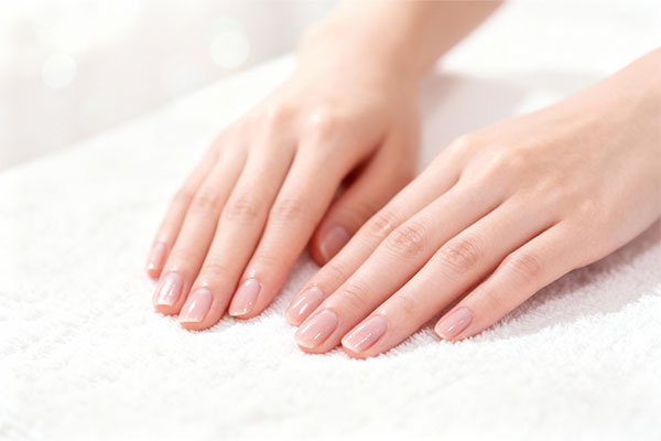 دست‌های نرم و مرطوب با ناخن‌های براق با استفاده از کرم مرطوب کننده آرگان برگامیا